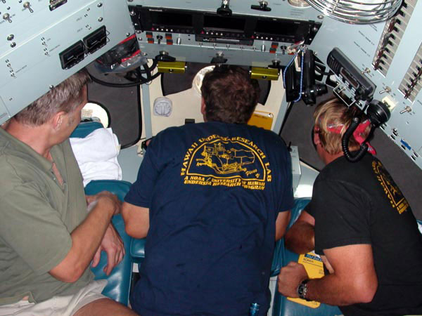 The pilot looks out the center viewport and the co-pilot and observer look out the other two windows.  This view is looking down through the open hatch before a dive.