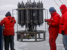 Mike Kong, Dan Torres and Marshall Swartz stand by as the conductivity, depth and temperature (CTD) recorder, mounted to the circular rosette along with many Niskin water bottles, returns after a cast at one of the iciest stations. The CTD and associated recorders help define properties of the water samples, which helps scientists understand where the sampled water came from, and where it is headed.