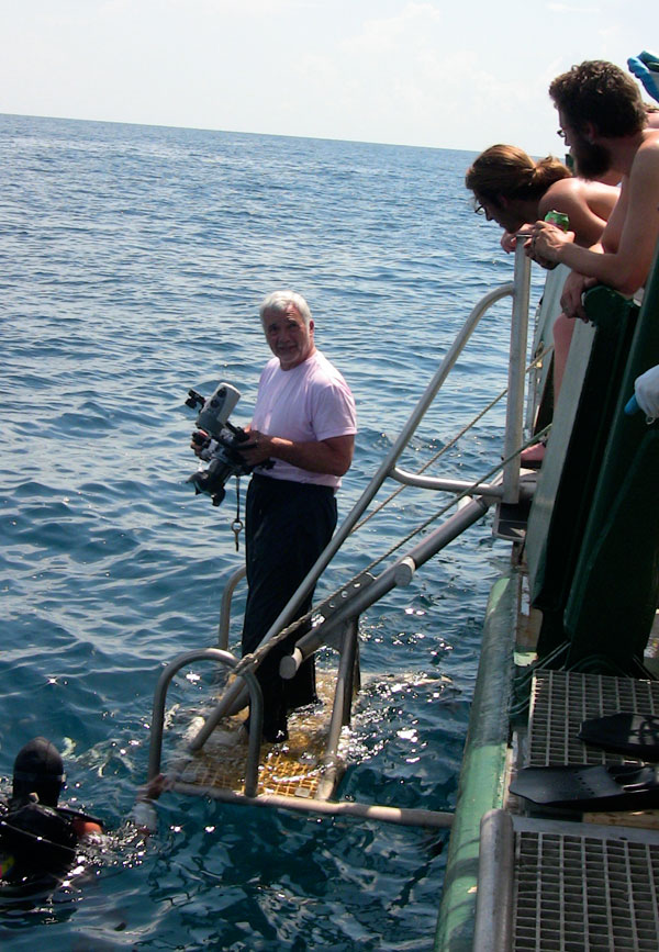 Principal Investigator, Dr. Adovasio, hands off an underwater video camera to divers. 