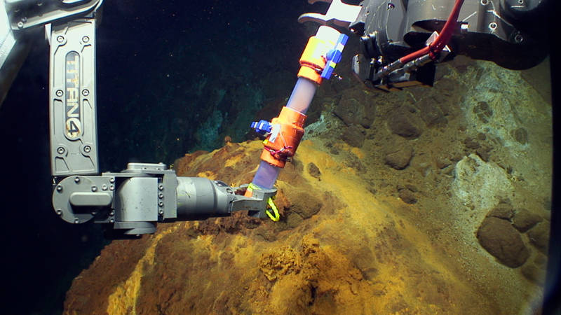 The Jason manipulator arms use a Scoop sampler to collect iron-oxidizing microbial mat at NW Eifuku.