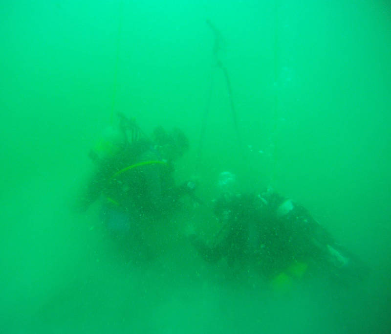 Divers forcing a hydraulic probe into the seafloor.