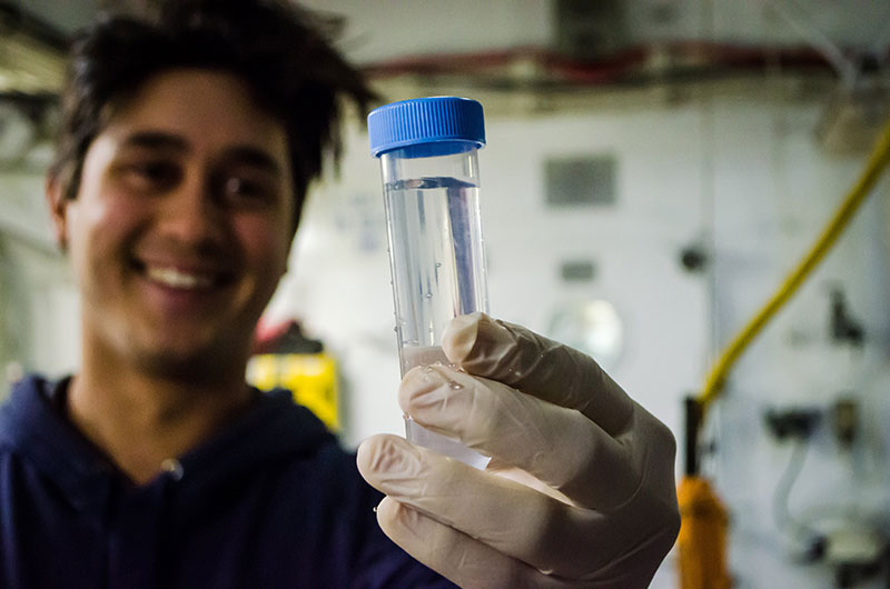 Brian Ulaski holds up a water sample from the CTD that he will filter for microbes.