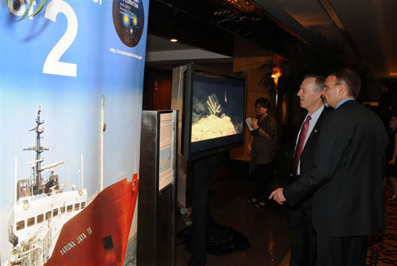 >Deputy Chief of Mission, Ted Osius (right) and David McKinnie (left), NOAA liaison to the US Embassy-Jakarta watch video from the <em>Okeanos Explorer</em> INDEX 2010 Expedition during the US Embassy-Jakarta 4th of July Celebration.