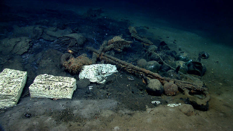The bow section of Monterrey B. Pictured here are glass demijohns, what has been tentatively identified as blocks of tallow and roles of cattle hides, and a large iron anchor. Intrusive modern fishing line is entangled on the shipwreck.