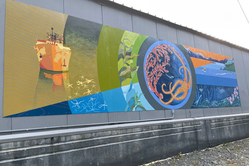 A large ocean-exploration themed mural on the side of a building.