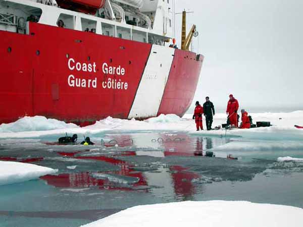 While safety personnel monitor the tethers, two divers prepare for another descent to search for life below the ice