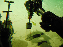 The manipulator arms pushing a tube-core into the sediments.