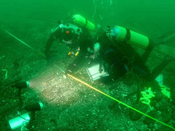 Archaeologists, working in 47 degree water, carefully draw the timbers used to build the ship's the lower hull.