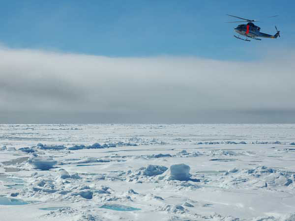 The North Slope Borough Department of Search and Rescue (NBSAR) helicopter approaches the HEALY over ice-covered waters.