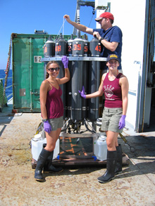 Christine Desautels and Monica Heintz work with research technician Nathan Buck to extract water samples from a recently recovered CTD/Niskin Rosette cast containing plume water samples.