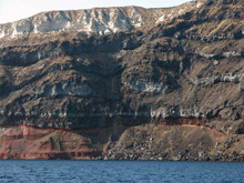 Ash layers, lava flows, pyroclastic deposits and other volcanic products exposed on the steep caldera walls of Santorini.