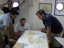 Members of the science team look at a map of Milos island.