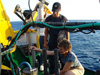 Aggelos Malios watches as WHOI senior research assistant Joanne Goudreau collects water samples.