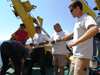 Professor Brian Bingham works with Aegaeo crew to deploy a transponder off the aft deck of the ship.