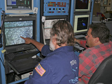 Ed Bowlby and Keith Tamburri  pointing at colonies of Lophelia pertusa on monitors. 