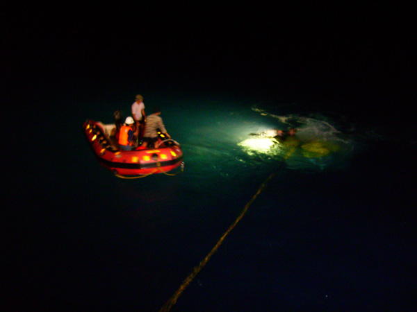 Fig. 2. The ROV rescue party watches from the rubber boat as Nick Caloyianis hooks the disabled ROV onto the winch wire so that it can be hoisted onto the deck.