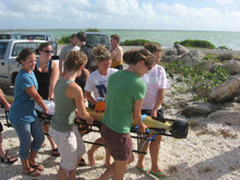 Girls from the University of Delaware Bonaire Study Abroad Program carrying an AUV toward the water.