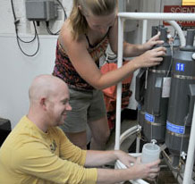 Jay Lunden gets help from Lara Miles in collecting water samples from Niskin bottles mounted on the CTD rosette. 