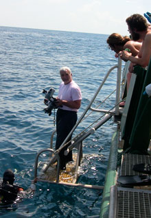 Principal Investigator Dr. Adovasio hands off an underwater video camera to divers. 