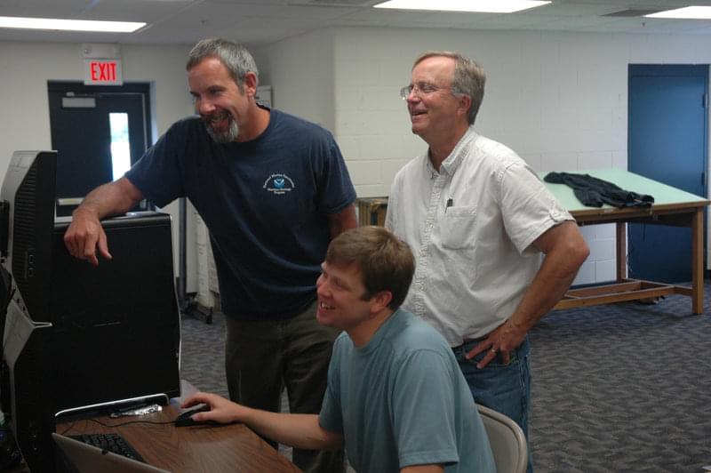Mark Story (front), shown with Russ Green (left) and Charlie Loeffler, has spent the last few days at his computer learning more about the Lake Huron region and refining the data collected by ATLAS.