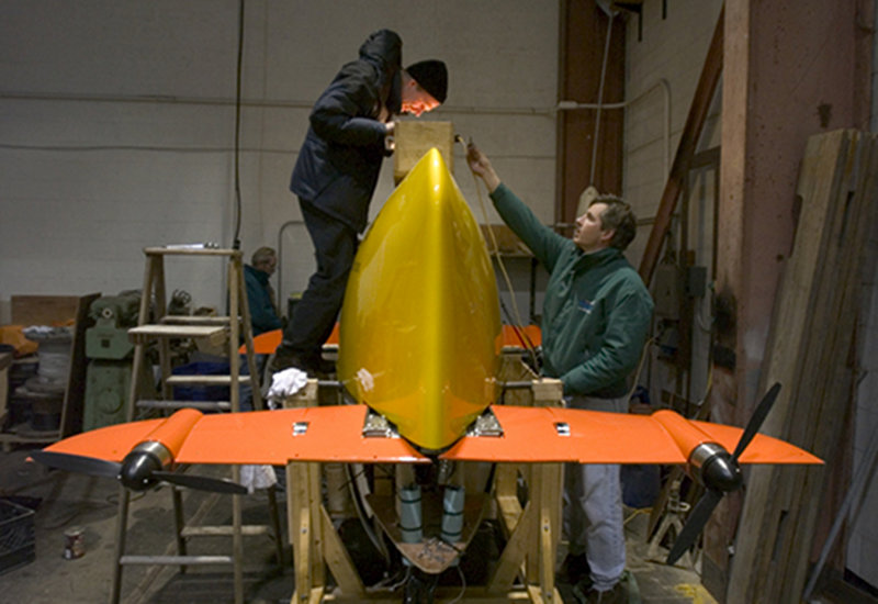 WHOI engineers Bob Brown (left) and Tito Collasius check the fit of the yellow outer skin over the lifting eye of the Sentry autonomous underwater vehicle.