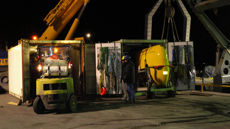 Sentry (on the right) has already been slid out of its van far enough to be ready for a crane-lift aboard ship. Now, TowCam is about to be pulled out of the left-hand van as Tim (yellow hat) and Greg (blue) look on. Note the shoulder-high size of the wheel for the 70-ton crane visible to the left of, and behind, the TowCam container – that’s a serious-sized piece of equipment!