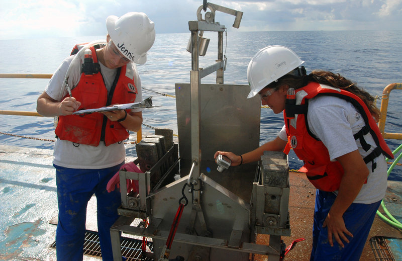 Jennie and Janessy document the box core after it is brought to the surface, filled with Gulf of Mexico deep-sea sediment.