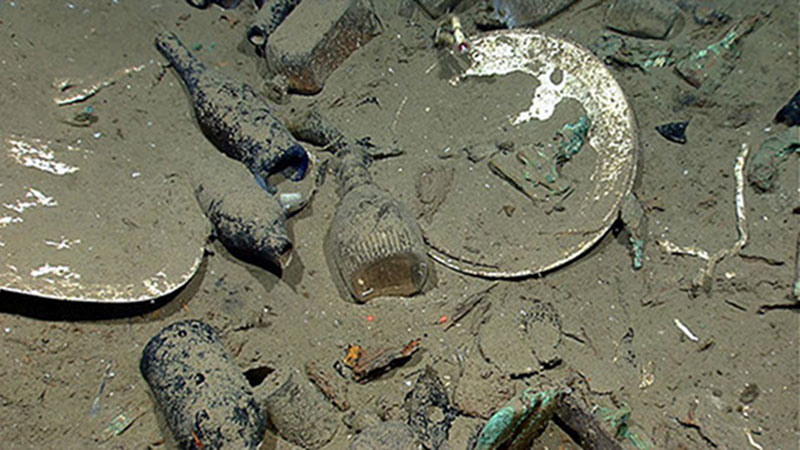A variety of artifacts inside the ship's hull relate to daily life on board. Artifacts include ceramic plates, platters, and bowls; and glass liquor, wine, medicine, and food storage bottles of many shapes and colors (some with the contents still sealed inside). Image courtesy NOAA Okeanos Explorer Program.