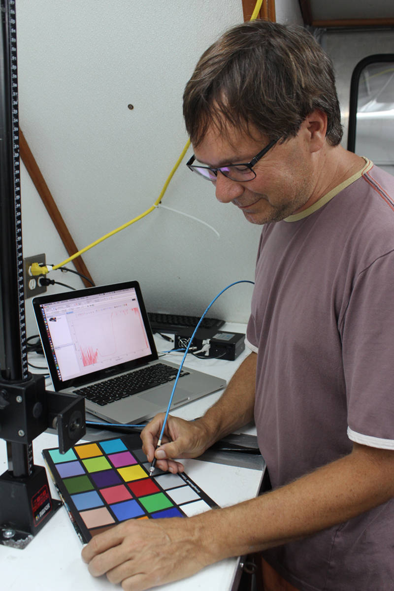 Sönke Johnsen holds the fiber optic probe to a color standard. The spectrometer is to the right of the computer, which is displaying the spectrum.