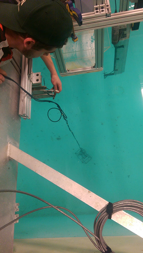 Devon lowering the drop camera system into the tow tank to begin the experiments.