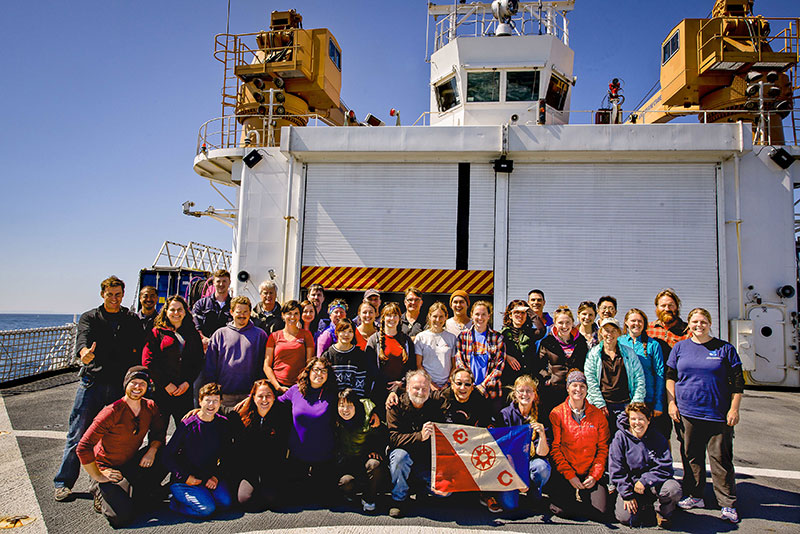 The science team poses with The Explorers Club Flag 61 on the helicopter deck of the USCGC Healy.