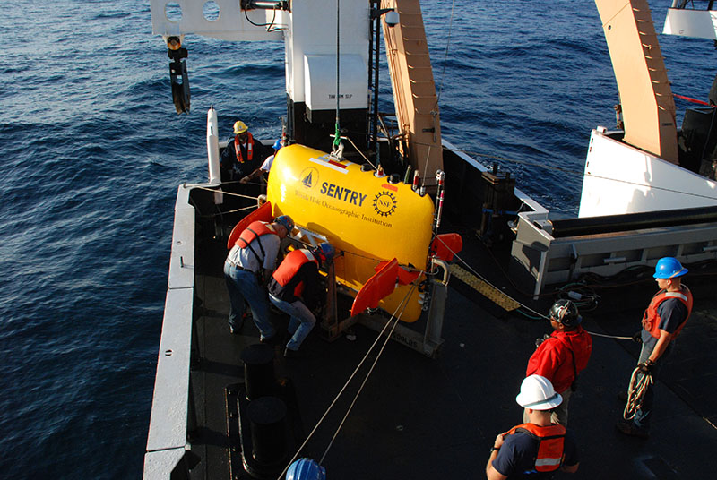 AUV Sentry engineers Andy Billings and Jennifer Vaccaro remove Sentry’s cradle so that it can be safely lifted by the ship’s crane and deployed in the water.