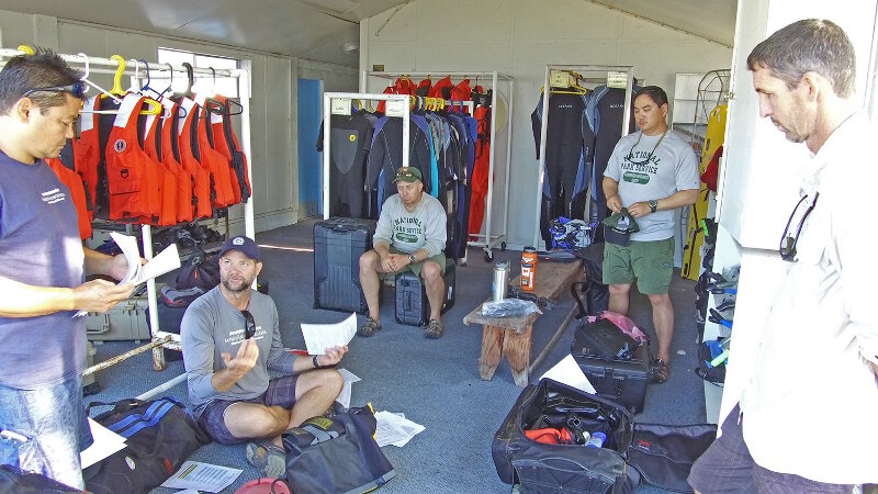 The team discusses safety protocol and the next day’s operations.