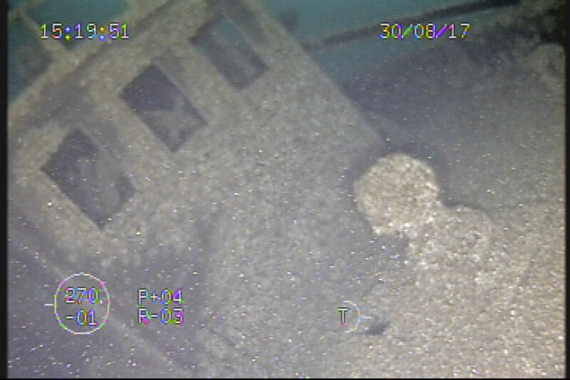 While hovering over the bow of the Ohio, the ROV imaged both the capstan and pilot house. Just inside the left windows of the pilot house, the ship’s wheel is visible.