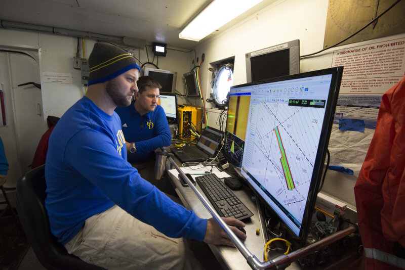Co-Principal Investigator Dr. Art Trembanis sits watch with University of Delaware doctoral student Carter DuVal. Together, they monitor incoming sonar data and manage the navigation plan as the vessel’s captain steers a pre-planned course.