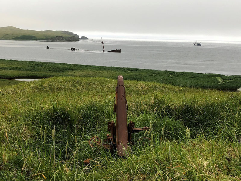On Kiska Island overlooking a cannon, sunken ship, and Norseman II.