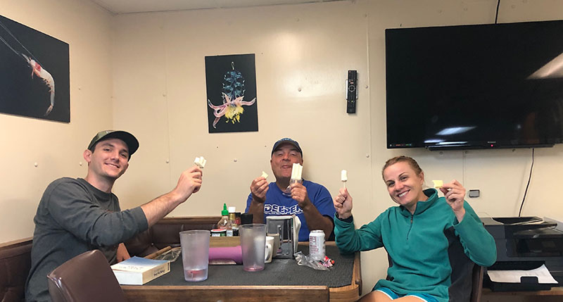 L-R, Alexander Davis, Tracey Sutton, Ph.D., Heather Bracken-Grissom, Ph.D. enjoying coconut ice cream bars and discussions with colleagues while waiting on the rain to pass!