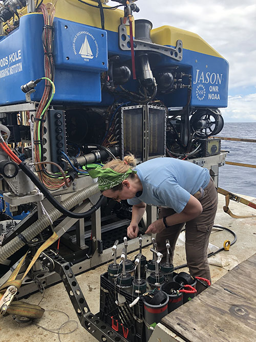 Before every dive, the DEEP SEARCH team will work with the Jason operators to decide on a plan for the sampling basket. Scientists bring their own specialized sampling gear with them, and the Jason team secures the gear on the basket before every dive. Here, Amanda Demopoulos prepares her sediment push cores before the first dive.