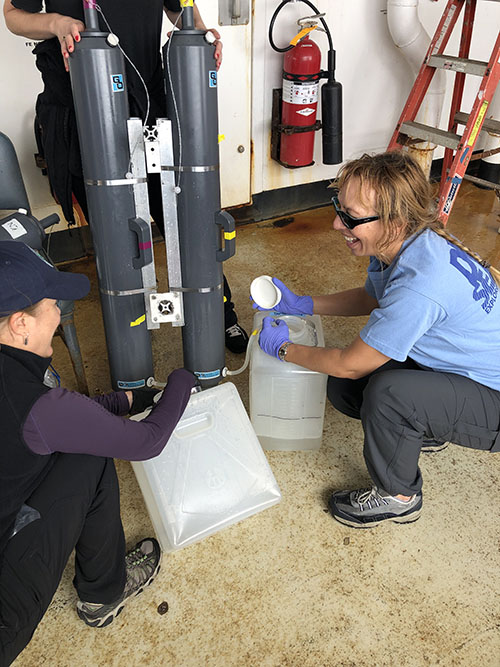 Cheryl Morrison and Christina Kellogg collect water from the two Niskin bottles after they were removed from the ROV post-dive.