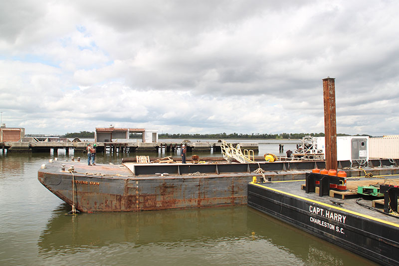 This barge (back) and barge crane (front) were used to load all large equipment for the ROV Jason and DEEP SEARCH science teams. By the time this photo was taken, much of the equipment had already been transferred to the Ron Brown, and only a couple of vans (far right) remain on the barge.