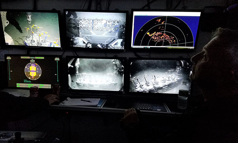Structure of shipwreck visible on scanning sonar (display at top right) while ROV operator Paul Sanacore prepares to collect a sediment core with the manipulator arm.
