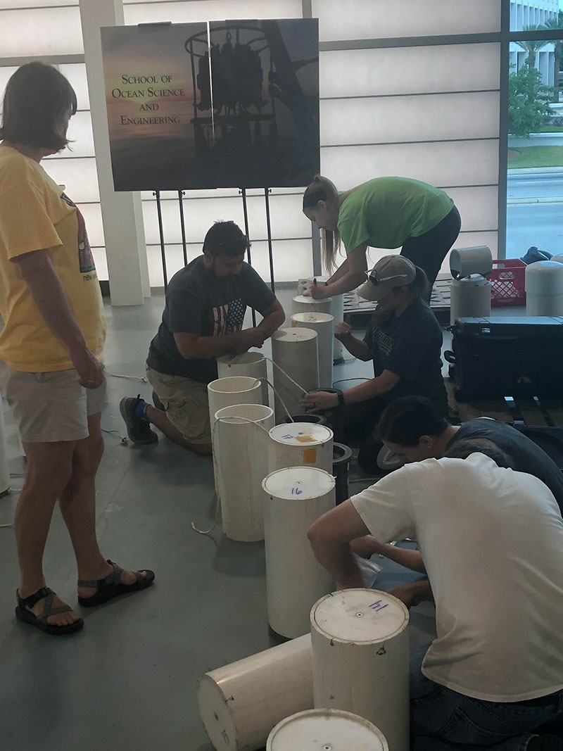 The whole team pitches in to set up microbial recruitment experiments – it involves tools, knots, many cable ties, and a boat load of teamwork.