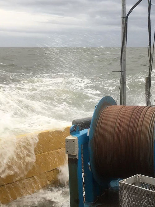 Storm swells break over the side of the survey vessel.