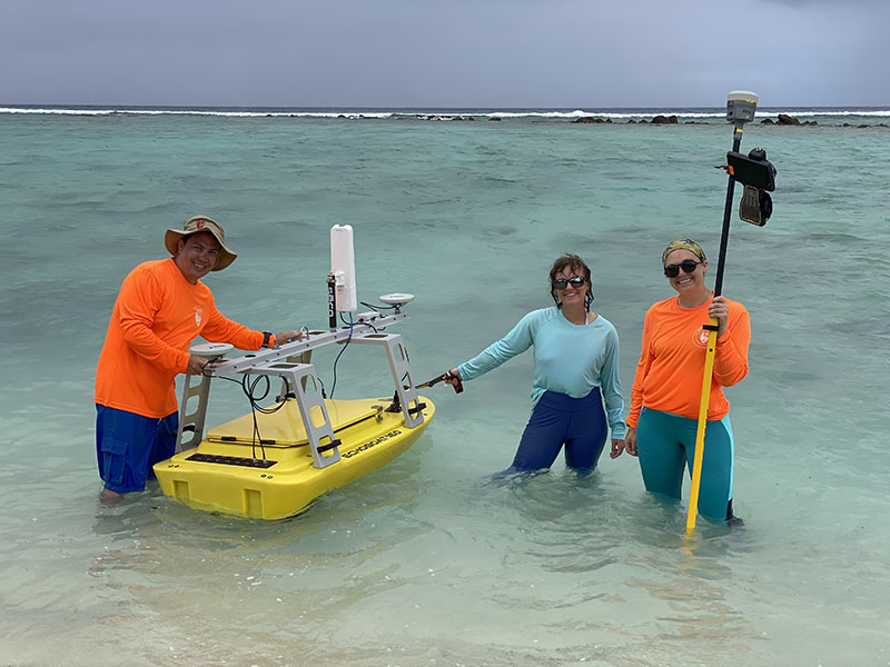 Tahzay Jones, Olivia Helinski, and Liza Hasan deploying an uncrewed surface vessel to collect multibeam data along the line of newly discovered blast craters at the Asan unit of War in the Pacific National Historical Park.