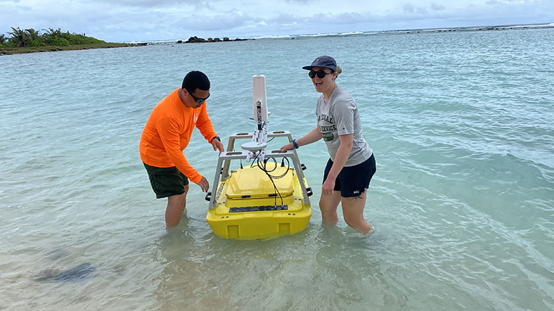 Tahzay Jones and Liza Hasan preparing an uncrewed surface vessel equipped with a multibeam sonar system for data collection inside the reef crest at the Asan unit of War in the Pacific National Historical Park.