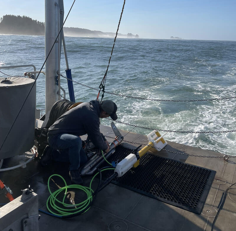 A project team member checks the connection between the side-scan sonar (left) and the magnetometer (right). The instruments were connected so the team only had to manage one tether.