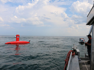 A trained DriX operator pilots a DriX for a nearby ship.