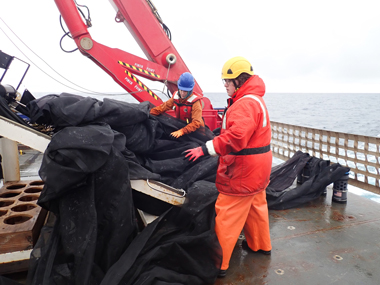 Moira Décima and Ronnie Balice (left to right) prepare the Multiple Opening/Closing Net and Environmental Sensing System (MOCNESS) for deployment during the Exploring Pelagic Biodiversity of the Gulf of Alaska and the Impact of Its Seamounts expedition.