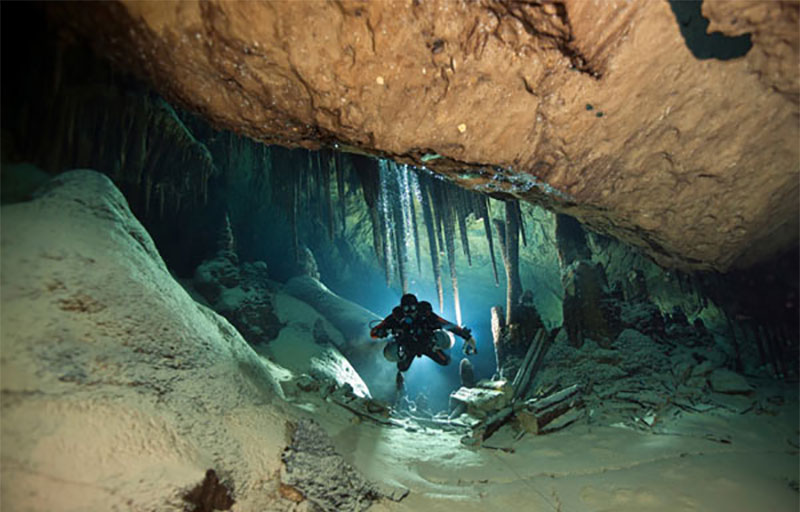 Stalactites hang from the ceiling of an underwater cave in Bermuda as a diver navigates through the system.