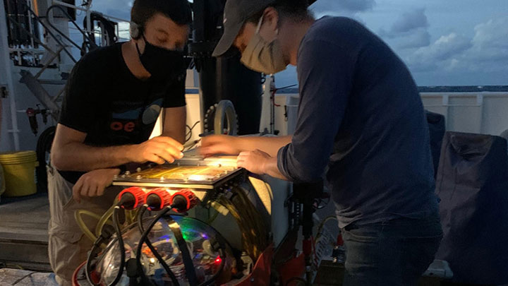 WHOI engineer Casey Machado (right) and NASA Jet Propulsion Laboratory engineer Andy Klesh (left) work on Orpheus after its recovery from a dive to push endurance capabilities on the vehicle.